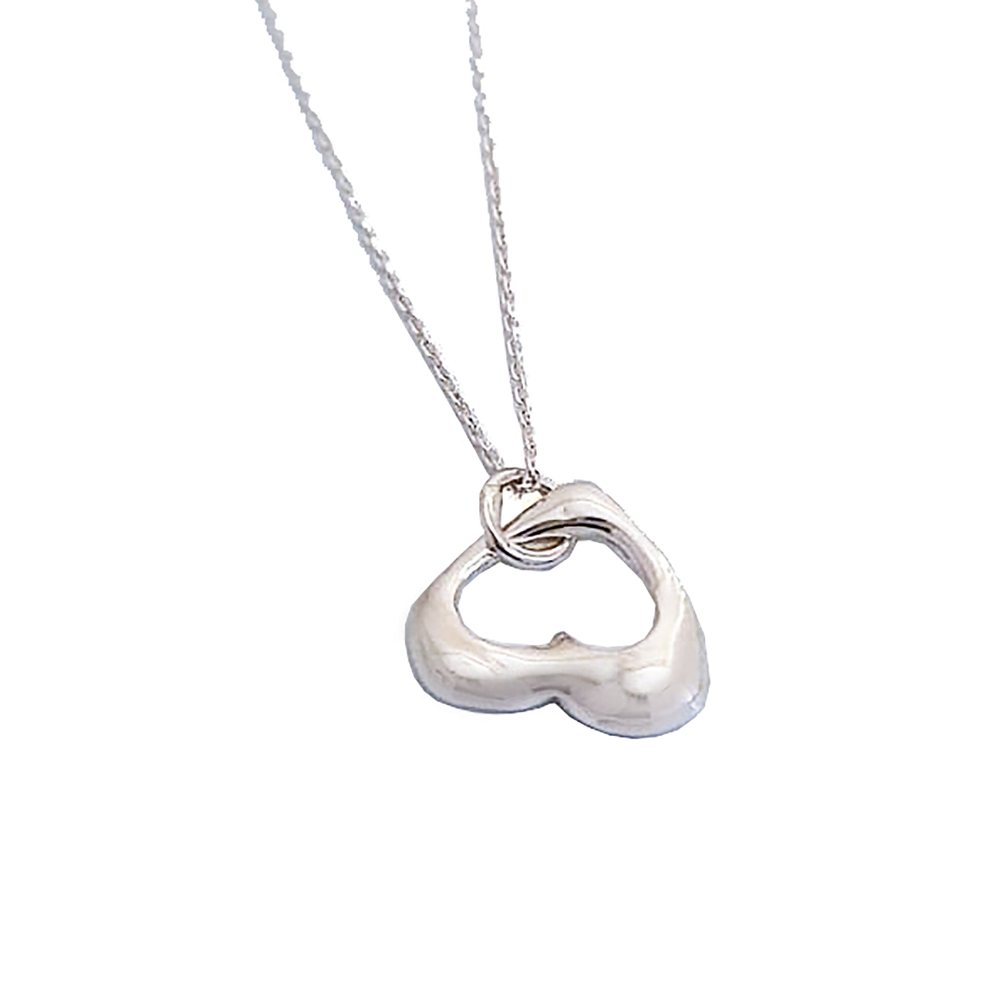 The Only Heart Necklace from FR | Art Jewellery showcases a delicate silver chain adorned with a heart-shaped pendant featuring an open center. The pendant’s smooth and shiny finish enhances its sleek and elegant appearance. This handmade piece of jewelry is simple yet stylish, making it perfect for everyday wear or special occasions.