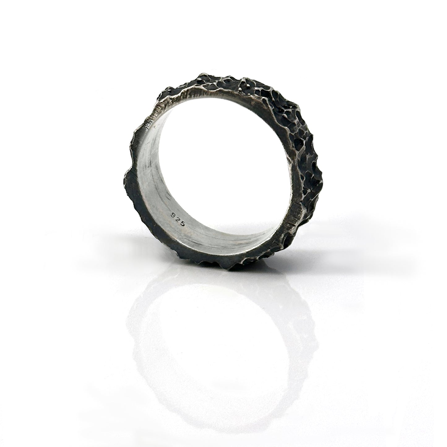 The Porocious Ring by FR | Art Jewellery features a rugged, textured silver surface reminiscent of natural rock formations. Its interior is smooth and polished, providing a striking contrast to the rough exterior. This piece of handmade jewellery is showcased upright against a plain white background.