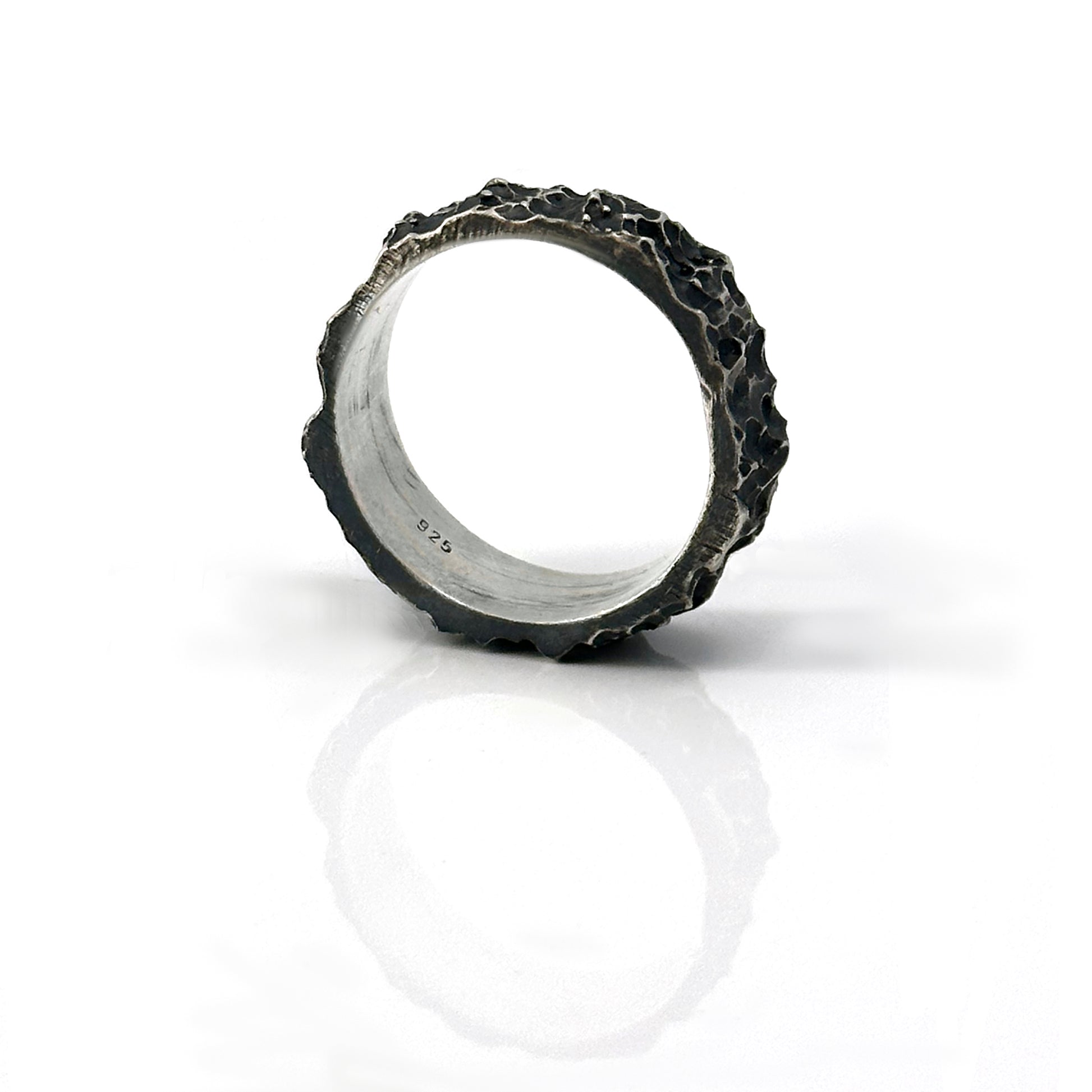 The Sterling silver Porocious Ring by FR | Art Jewellery is a handmade piece with a rugged, oxidised finish, shown upright on a white reflective background.