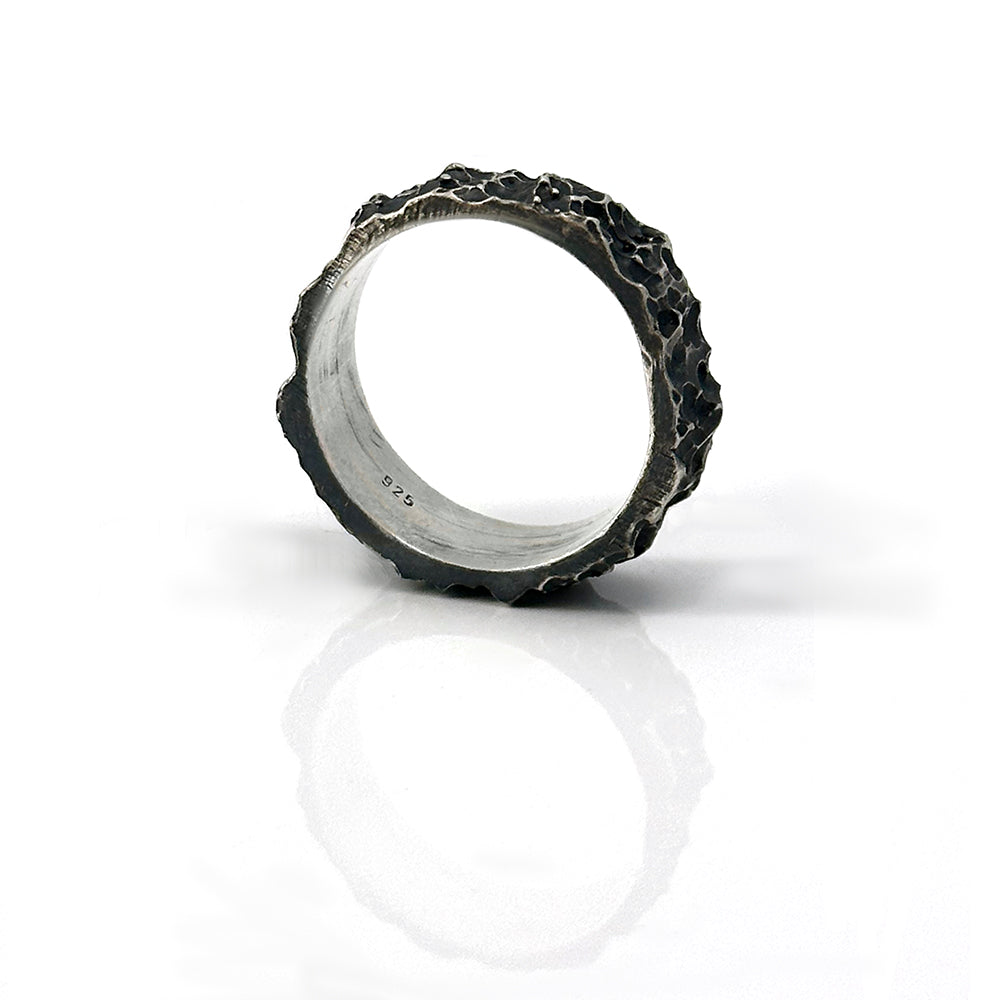 The Sterling silver Porocious Ring by FR | Art Jewellery is a handmade piece with a rugged, oxidised finish, shown upright on a white reflective background.