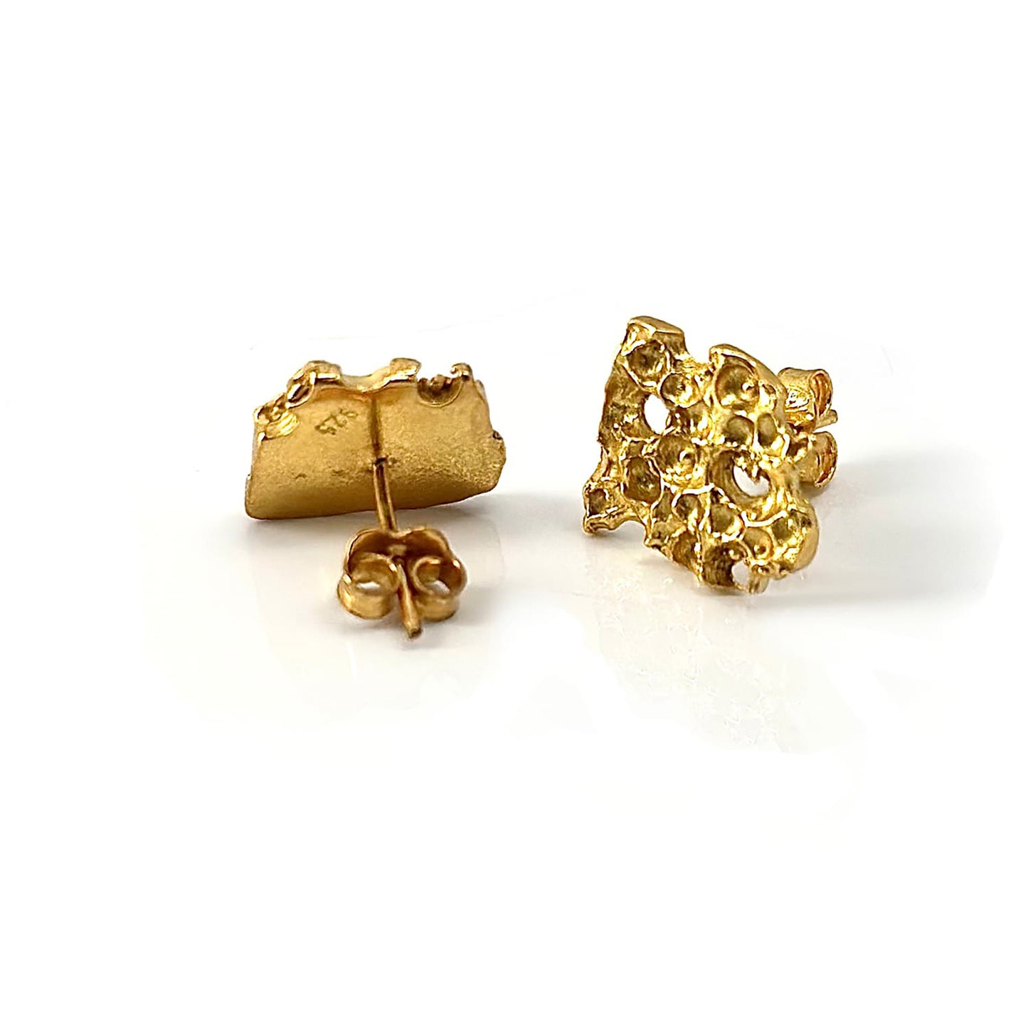 The Porocious Earrings by FR | Art Jewellery are a pair of small, gold-plated stud earrings featuring an abstract, textured design with multiple rounded indentations. This handmade jewellery is displayed against a plain white background, making it perfect for custom-made orders.