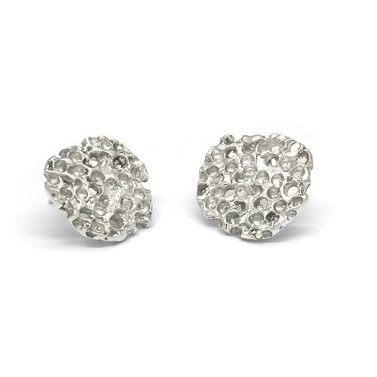 Introducing the Rock Earrings by FR | Art Jewellery: a pair of textured silver stud earrings with an organic, bubble-like pattern, showcasing the elegance of handmade jewellery. These round-shaped earrings have a shiny finish that reflects light flawlessly. Presented against a plain white background, these pieces celebrate artisanal craftsmanship.