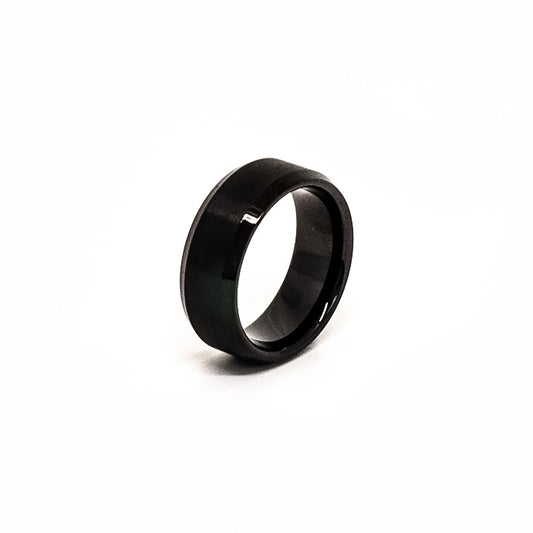 The Stainless Steel Black Bezel ring by FR | Art Jewellery, featuring a glossy, polished finish, stands upright against a white background.