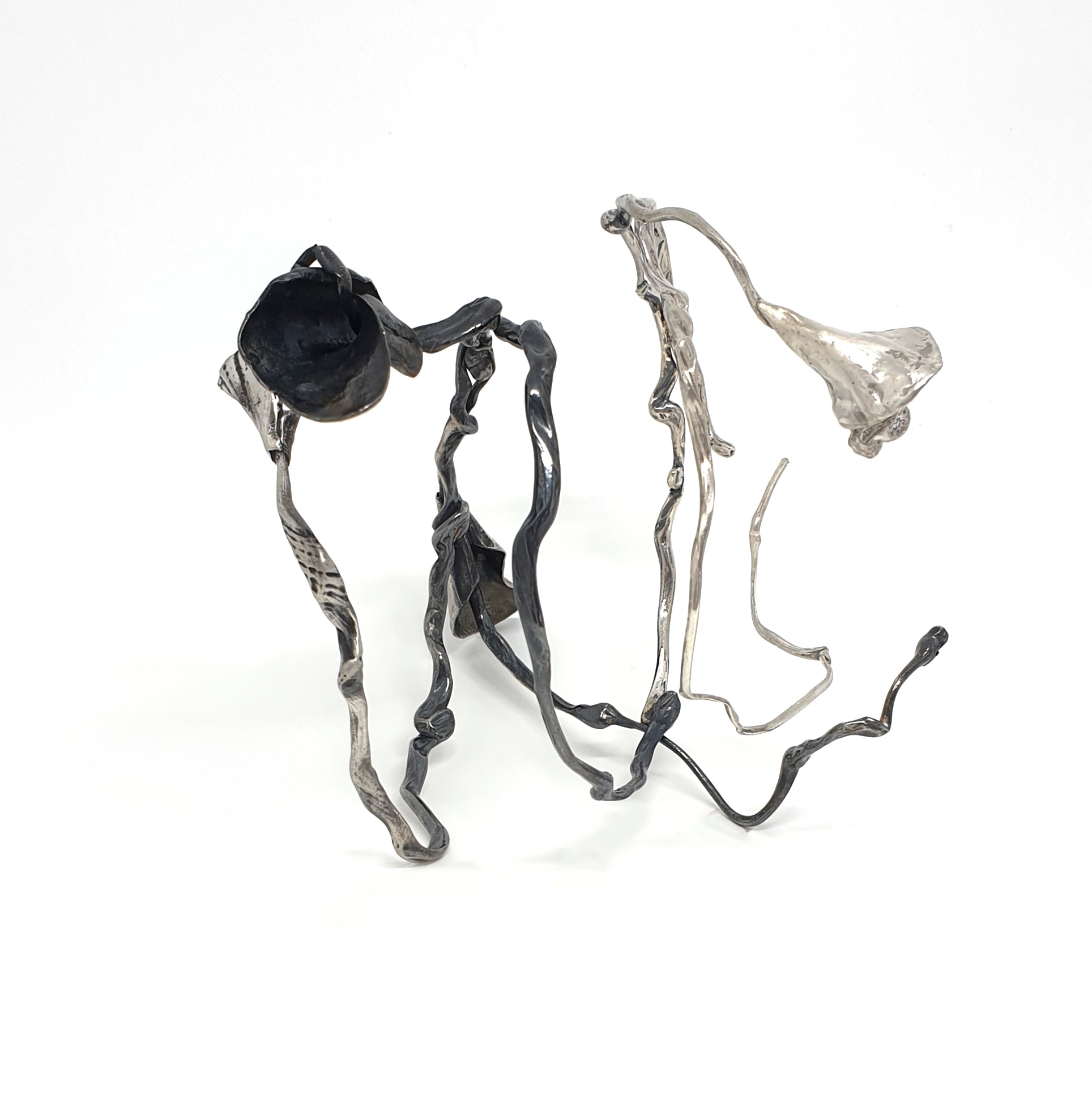 The Seaweed Bangle Sterling Silver by FR | Art Jewellery is an abstract metallic sculpture with twisting, irregular silver and black rods ending in organic, flower-like forms, displayed on a white background.