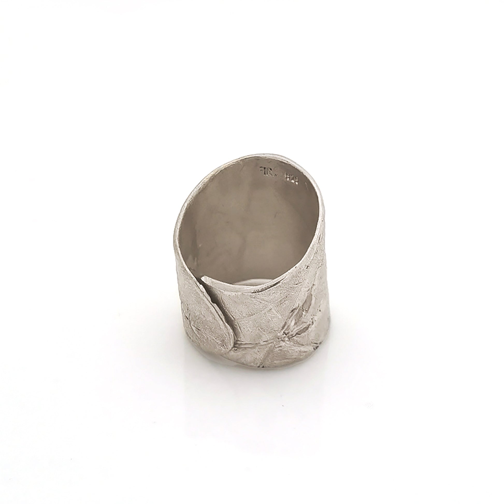 A wide, silver, adjustable "Silver Leaf Ring" by FR | Art Jewellery is placed on a plain white background. Part of the "Inspired by Nature Collection," the ring features subtle leaf patterns and has a textured, matte finish, giving it an organic and earthy appearance.