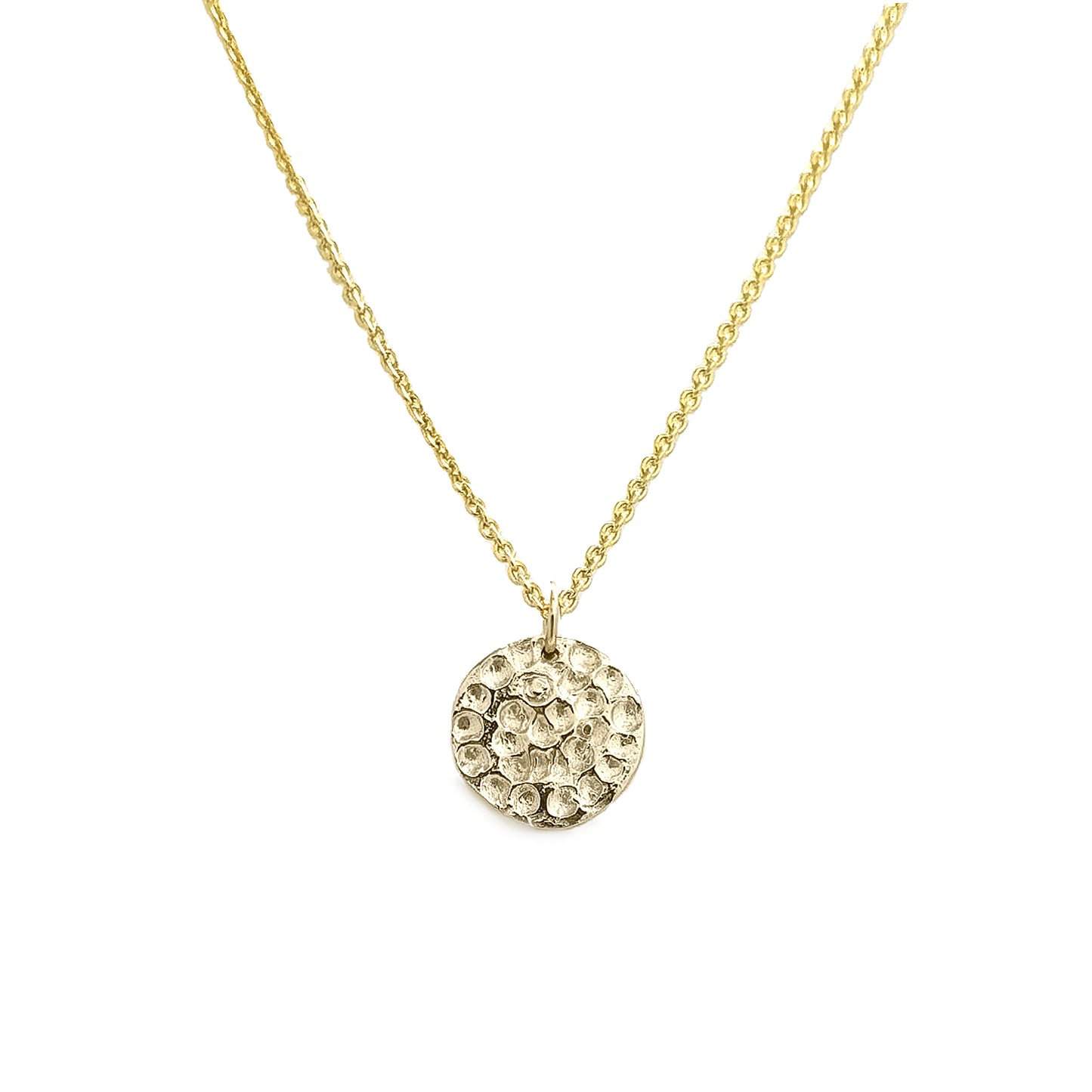 The Spot Necklace Big from FR | Art Jewellery is a silver necklace featuring a delicate chain and a round pendant. The pendant has a textured surface adorned with small, raised circular shapes that create an intricate pattern. Coordinating handmade jewellery, including custom-made gold-plated earrings, is also available to complement this exquisite piece.