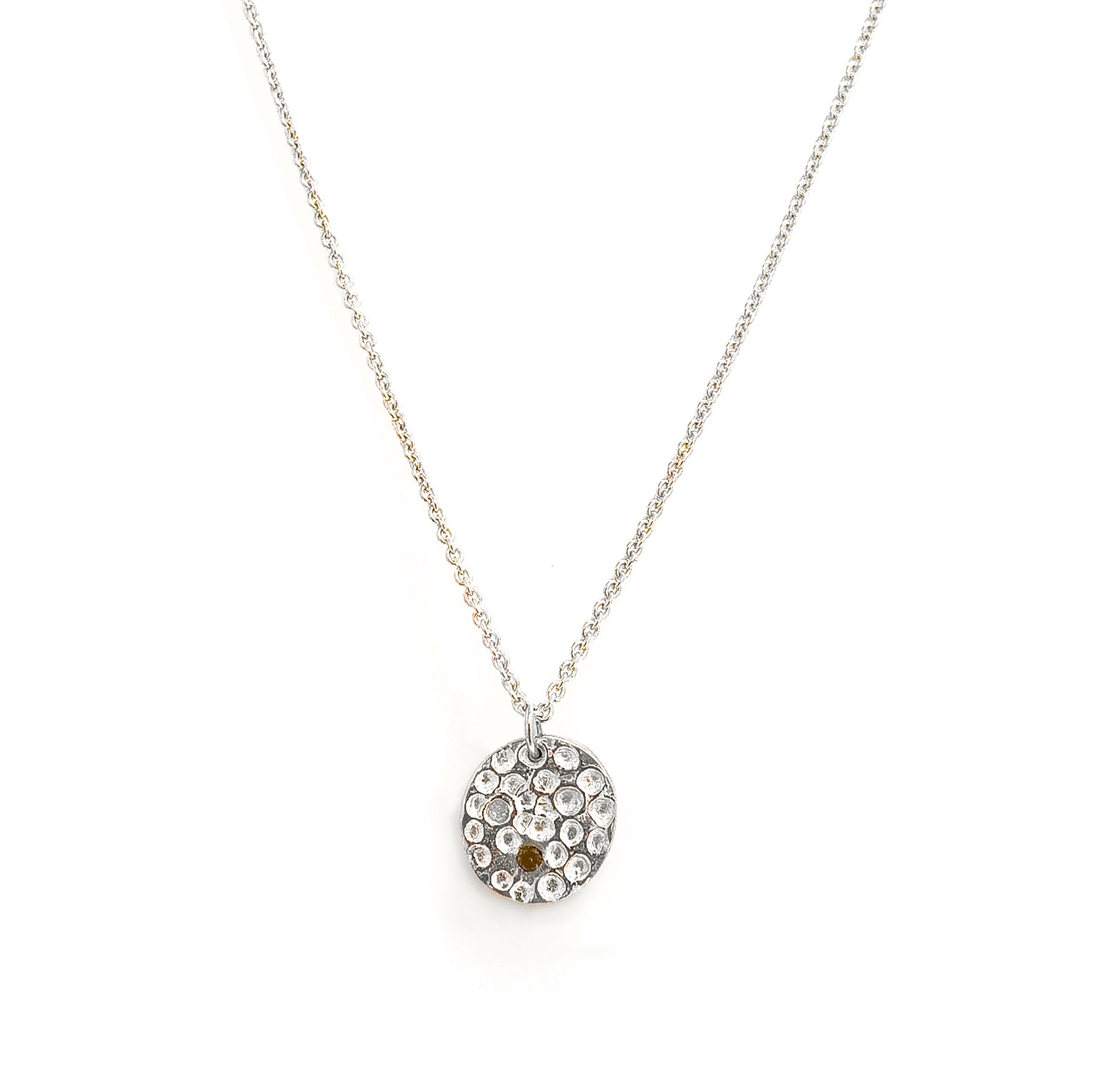 The Spot of Light necklace by FR | Art Jewellery features a sterling silver chain with a round pendant set with clear stones and a single citrine, showcased on a white background.