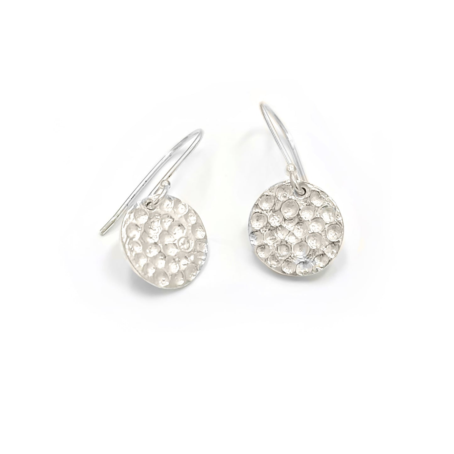 The Spot Earrings by FR | Art Jewellery are a pair of delicate sterling silver drop earrings, featuring textured circular discs hanging from simple hooks. The discs boast a hammered finish that adds a touch of sparkle, perfectly showcasing the elegance of handmade jewelry. These exquisite earrings are displayed against a plain white background.