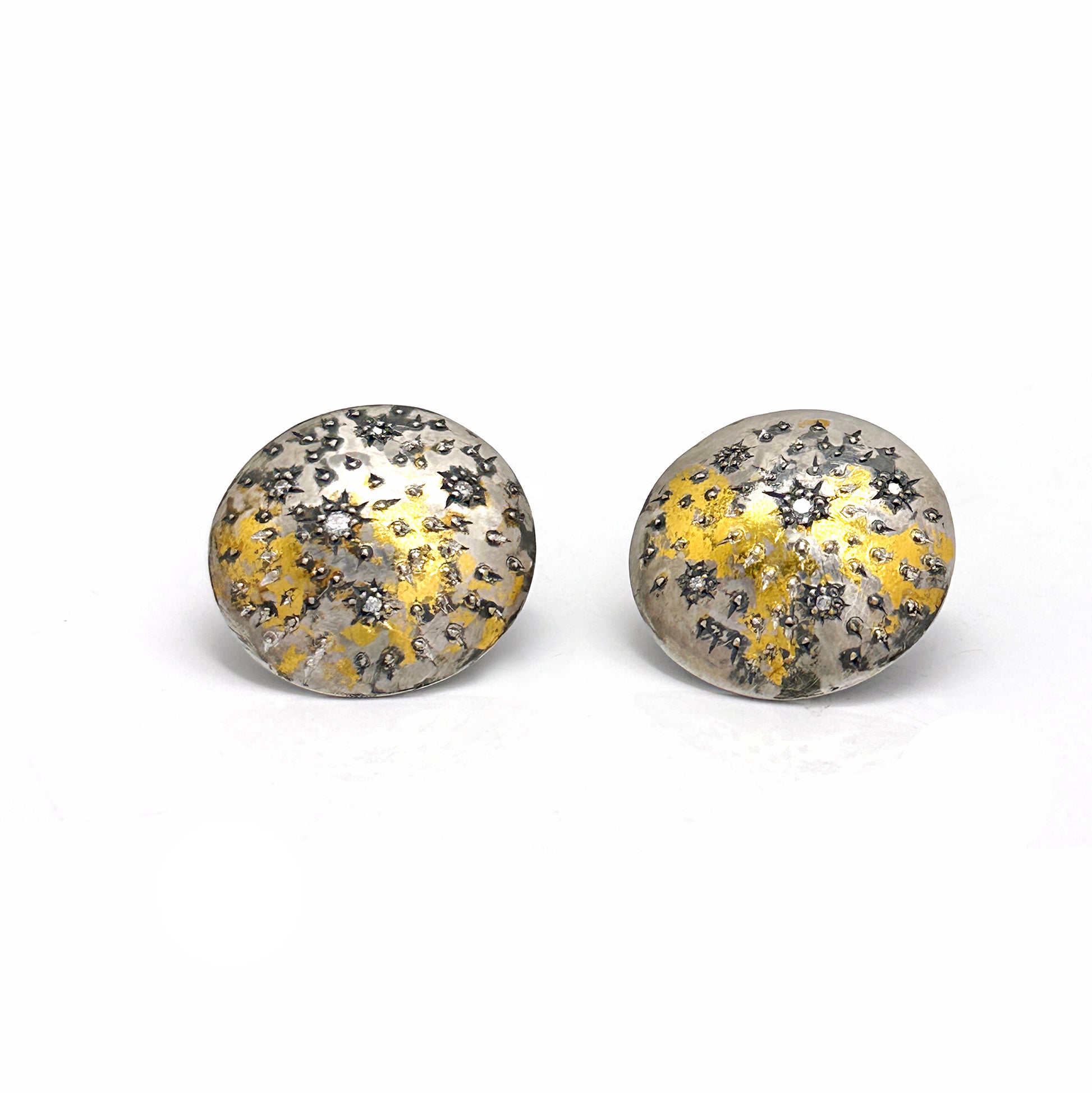 The Starburst Earrings by FR | Art Jewellery are a stunning pair of round metallic earrings with a textured surface, showcasing speckled patterns of gold and black on a silver base. This gold-plated, handmade jewellery design evokes the beauty of a starry night or cosmic theme, making it perfect for custom-made orders.