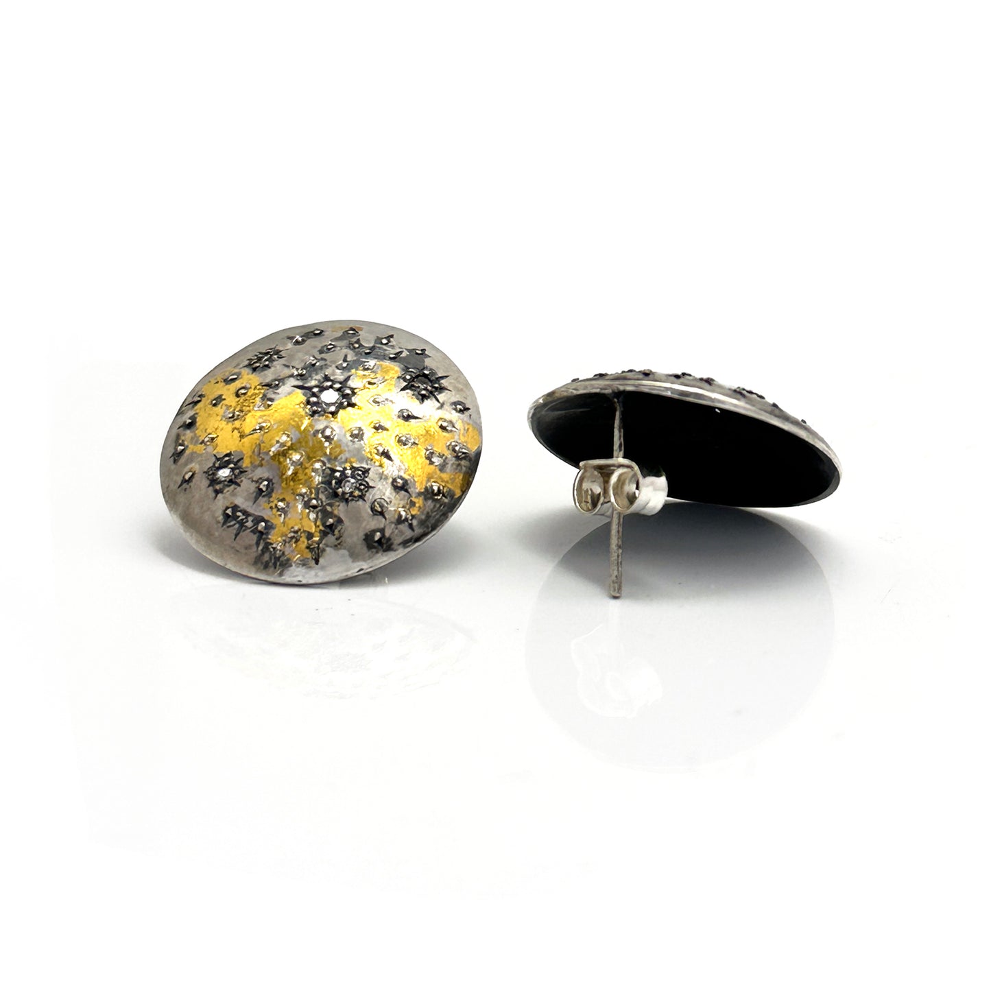 The Starburst Earrings by FR | Art Jewellery are a stunning pair of round metallic earrings with a textured surface, showcasing speckled patterns of gold and black on a silver base. This gold-plated, handmade jewellery design evokes the beauty of a starry night or cosmic theme, making it perfect for custom-made orders.