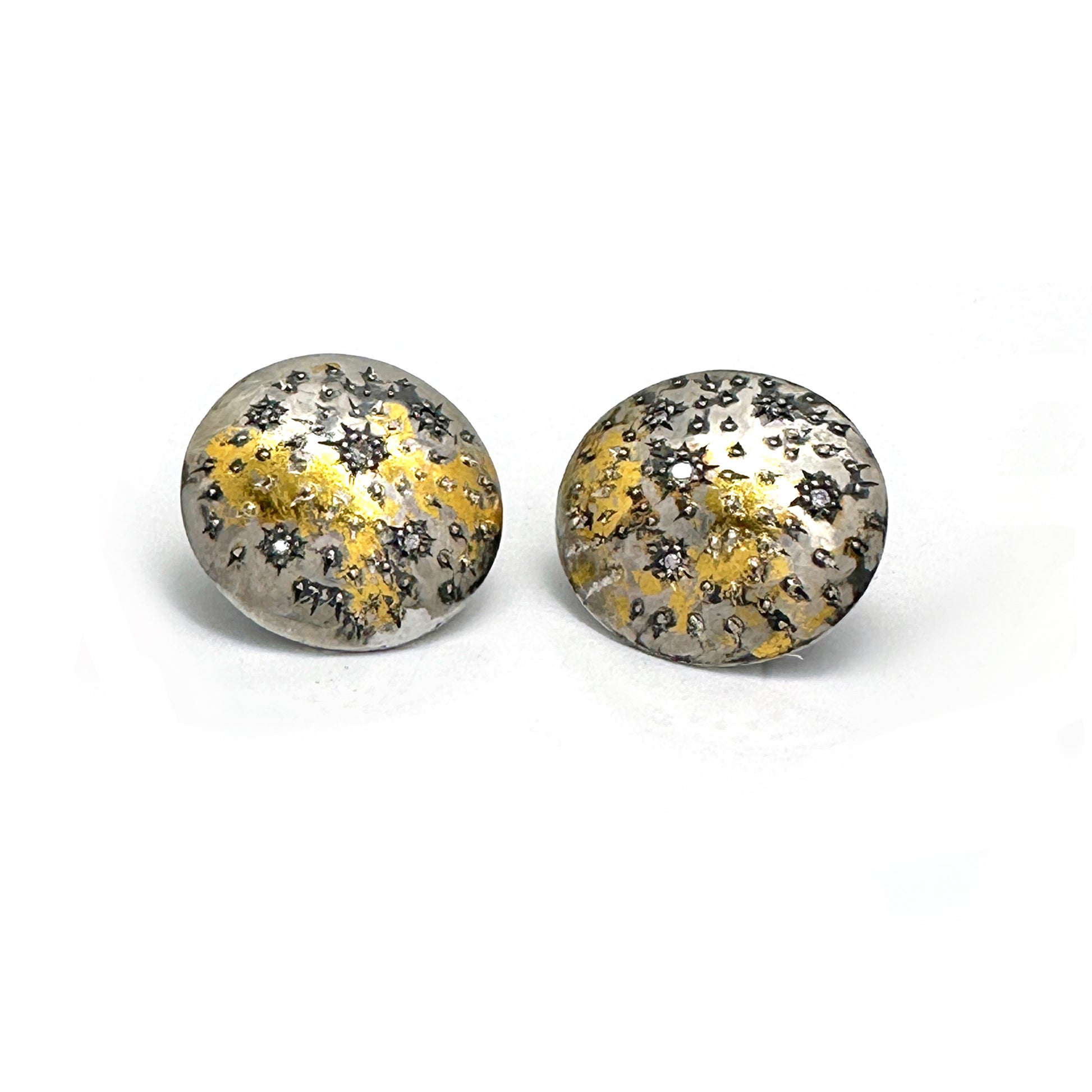 The Starburst Earrings by FR | Art Jewellery are a stunning pair of round metallic earrings with a textured surface, showcasing speckled patterns of gold and black on a silver base. This gold-plated, handmade jewellery design evokes the beauty of a starry night or cosmic theme, making it perfect for custom-made orders.