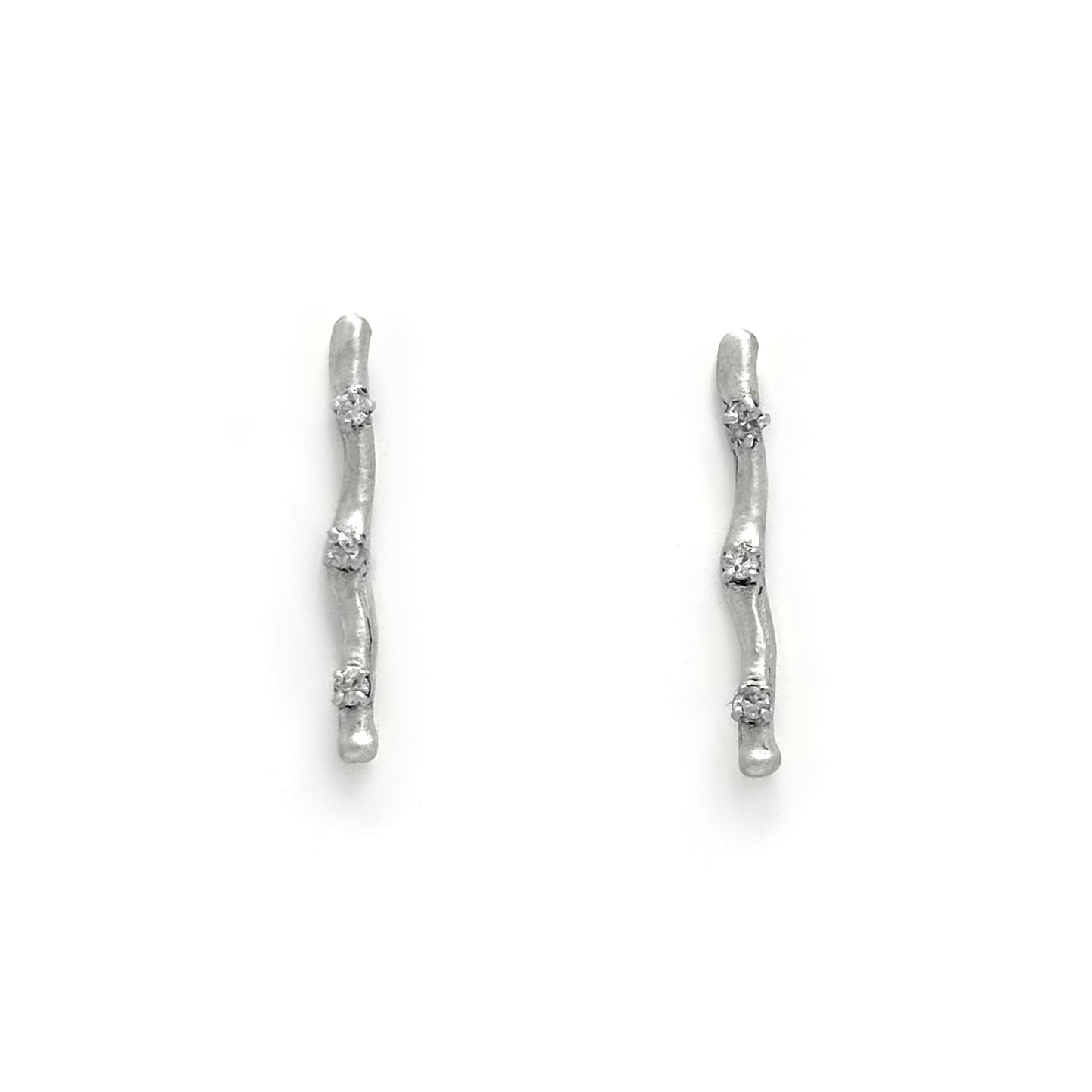 A pair of minimalist Stick Earrings by FR | Art Jewellery, crafted in sterling silver with a slender, slightly curved shape and an irregular surface texture. These Australian-made earrings are adorned with three small, evenly spaced embedded gemstones and are set on a plain white background.