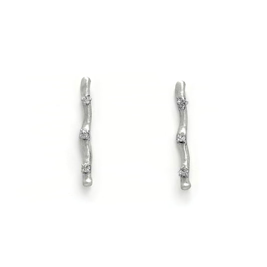 A pair of minimalist Stick Earrings by FR | Art Jewellery, crafted in sterling silver with a slender, slightly curved shape and an irregular surface texture. These Australian-made earrings are adorned with three small, evenly spaced embedded gemstones and are set on a plain white background.