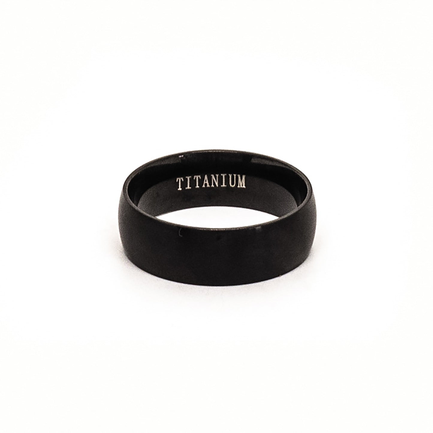 The Titanium Black Ring by FR | Art Jewellery is a comfort-fit titanium band with a black matte finish, shown upright on a white background and engraved with "TITANIUM" inside.
