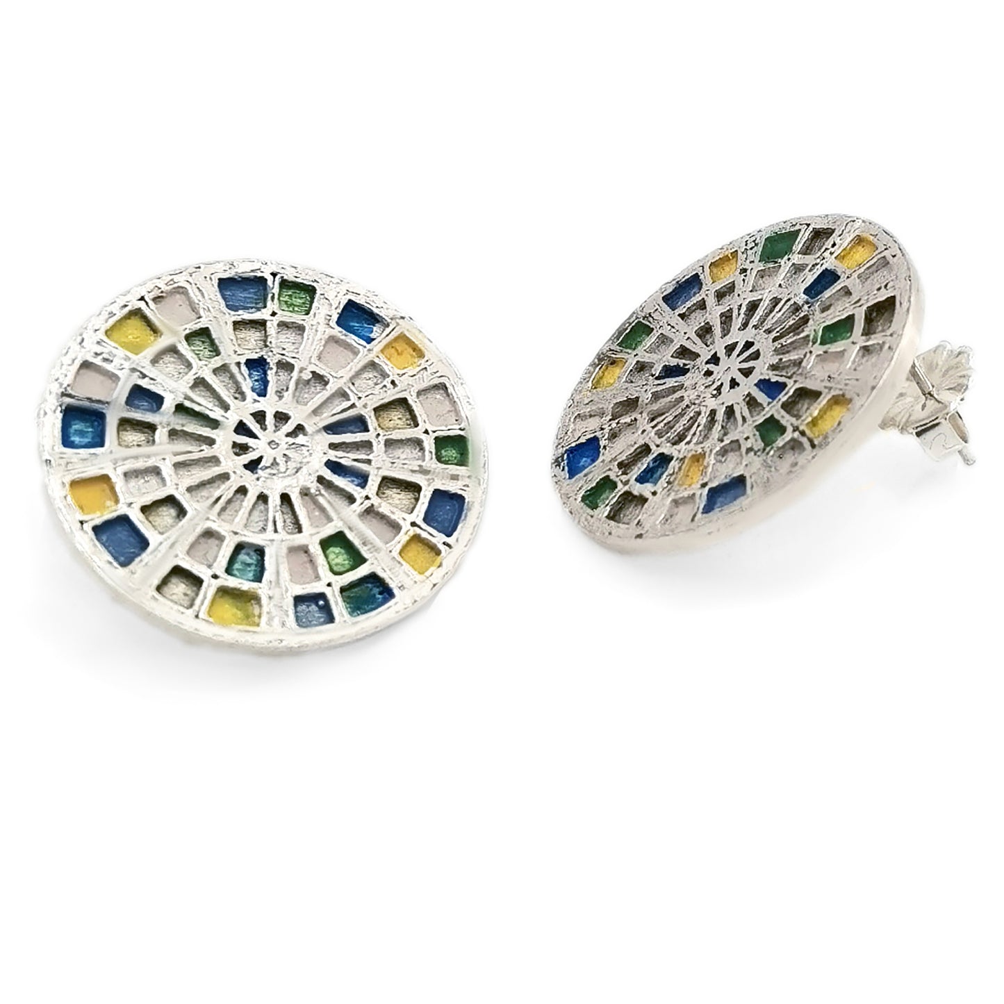 Introducing the Talis Earrings by FR | Art Jewellery, a stunning pair of round stud earrings designed with a stained glass window motif. These intricate pieces feature colored segments in shades of blue, green, and yellow, all beautifully set in silver-tone metal. Handmade to perfection, one earring is displayed front-on while the other is subtly angled.