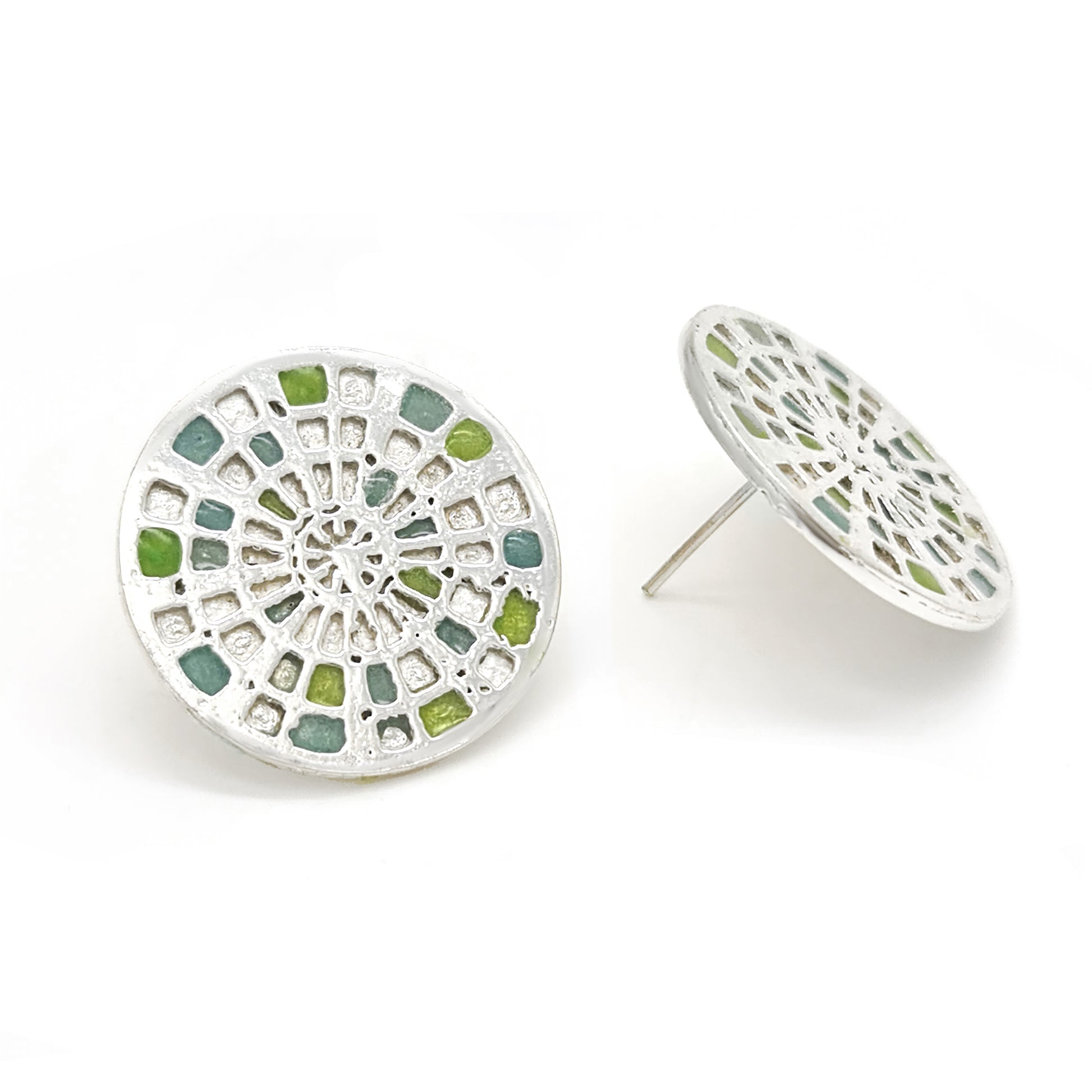 Introducing the Talis Earrings by FR | Art Jewellery, a stunning pair of round stud earrings designed with a stained glass window motif. These intricate pieces feature colored segments in shades of blue, green, and yellow, all beautifully set in silver-tone metal. Handmade to perfection, one earring is displayed front-on while the other is subtly angled.