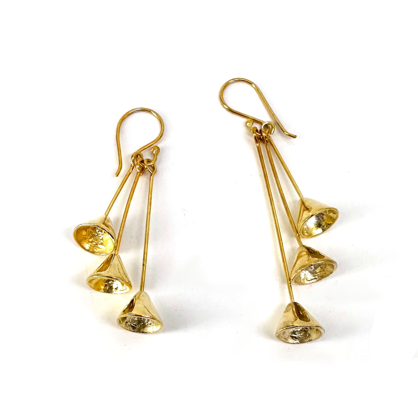 Introducing the Three Cones earrings from FR | Art Jewellery: a stunning pair of gold-plated earrings, each adorned with three dangling cone-shaped charms. These earrings feature hook-style backs and boast a shiny, reflective surface. This handmade design combines modern elegance, making it perfect for various occasions.