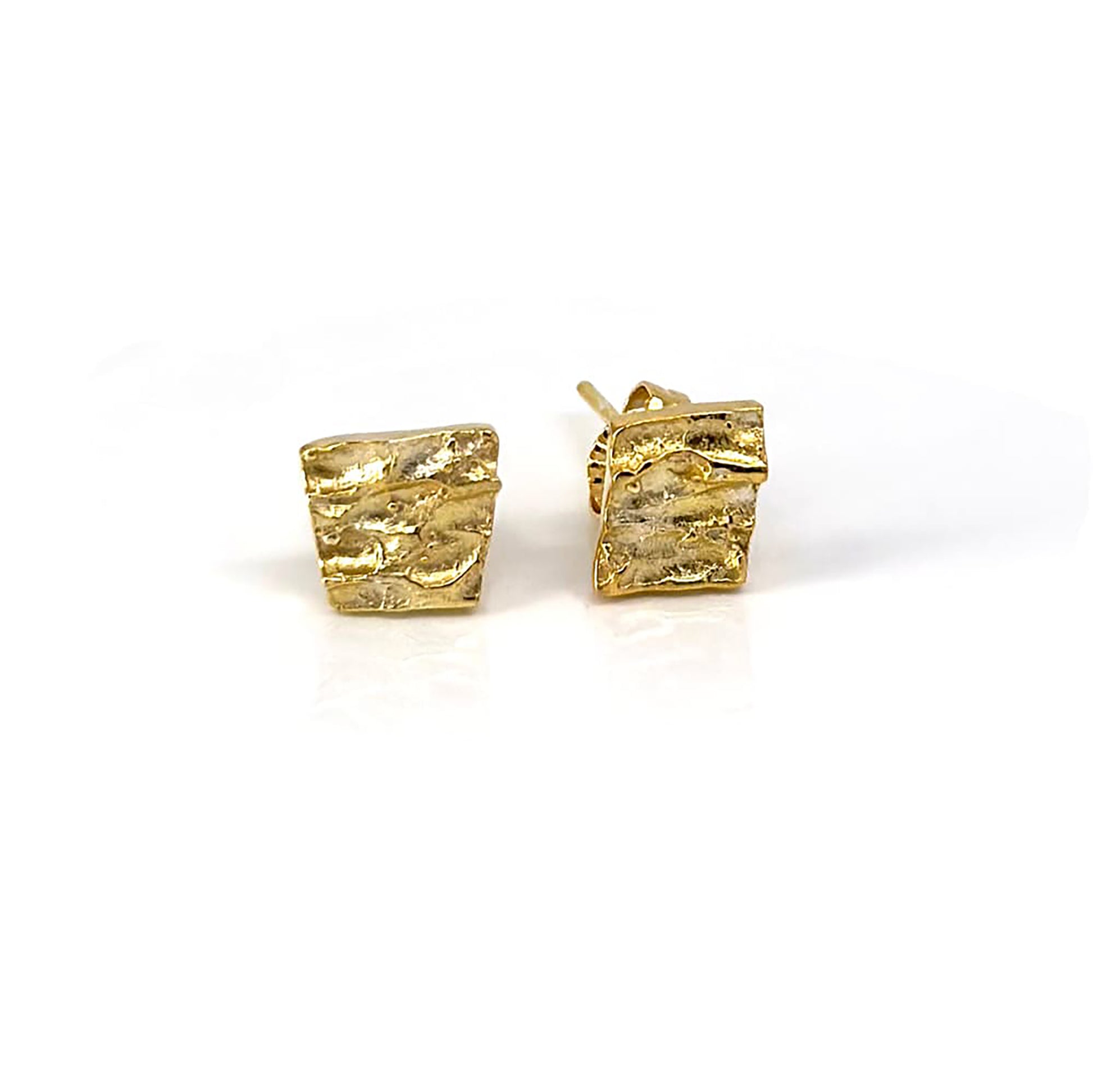 The Tribu Earrings by FR | Art Jewellery are displayed against a white background. These small, square-shaped gold-plated earrings feature a textured, wavy surface and come with standard post and butterfly backings, exemplifying exquisite handmade jewellery.