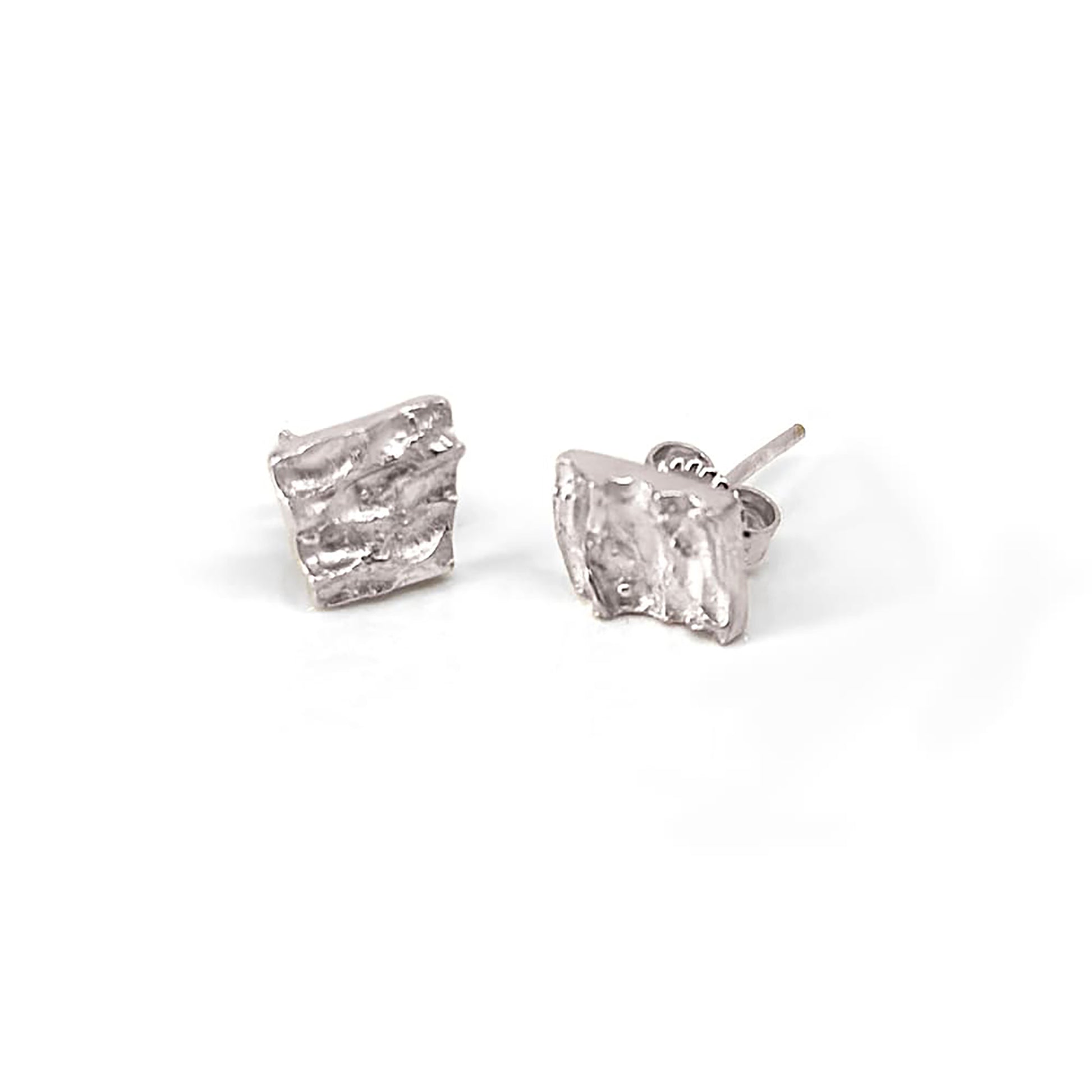 The Tribu Earrings by FR | Art Jewellery are displayed against a white background. These small, square-shaped gold-plated earrings feature a textured, wavy surface and come with standard post and butterfly backings, exemplifying exquisite handmade jewellery.