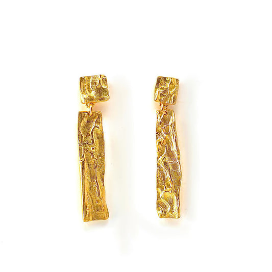 Introducing the Tribu Hoop Earrings by FR | Art Jewellery, a pair of textured, handmade gold-plated earrings with elegant rectangular shapes. Each earring showcases a small square stud at the top, seamlessly attached to a long, narrow vertical piece that subtly widens towards the bottom. The surface features an intricate hammered texture, ideal for custom-made orders.