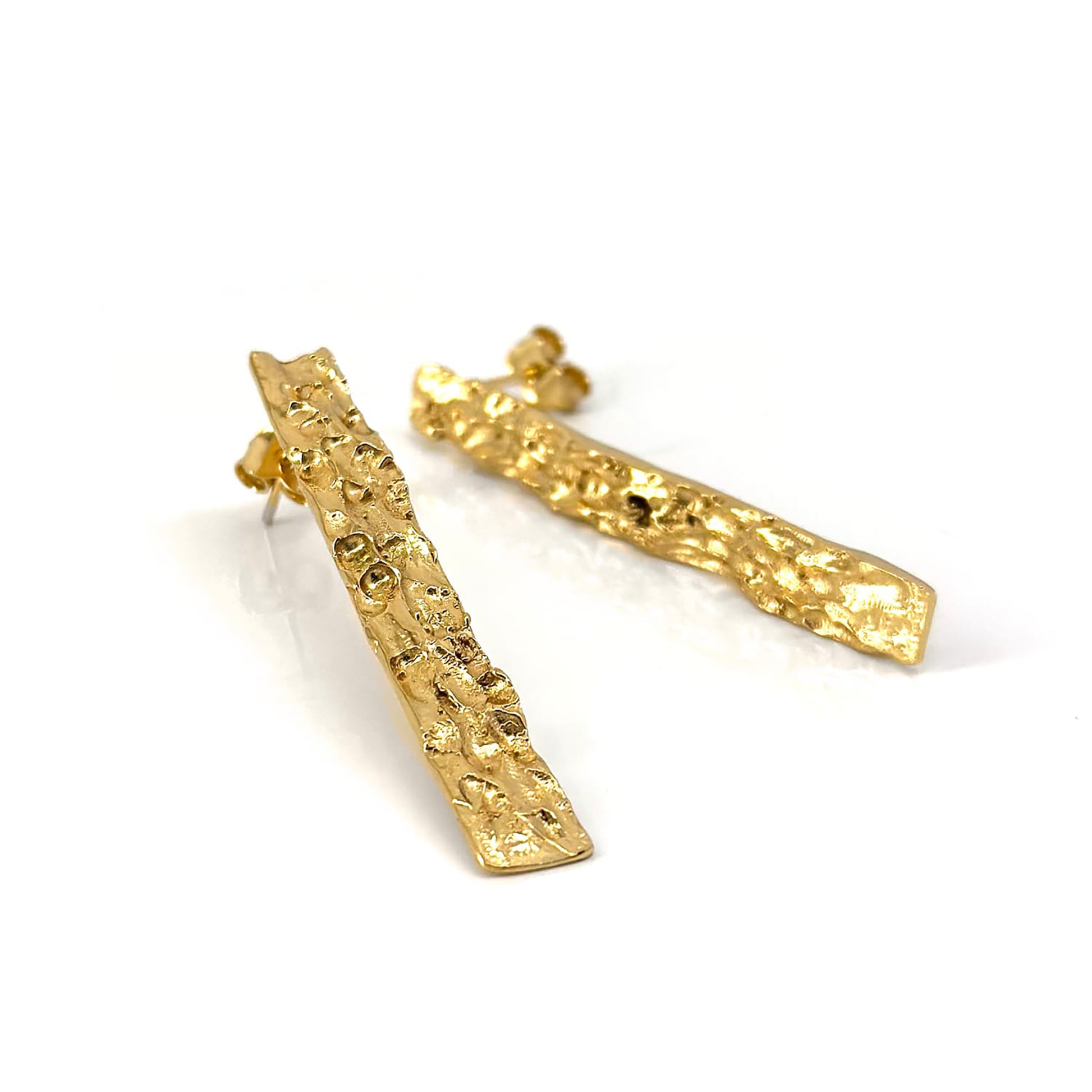 The Tribu Long Earrings in Sterling Silver by FR | Art Jewellery feature an irregular, organic shape and post backing, making a bold statement for your handmade jewellery collection. Shown lying on a white surface.