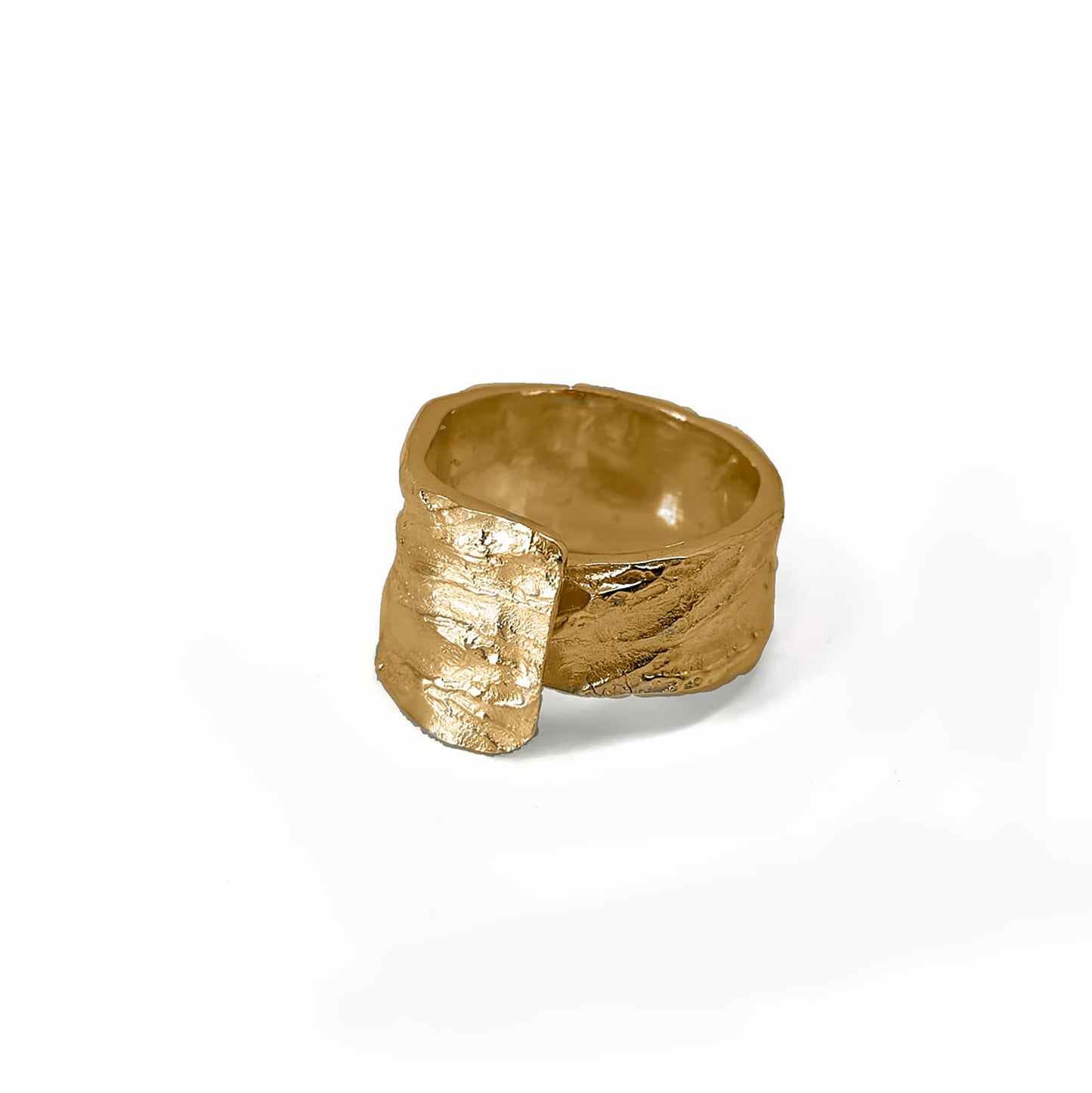 The Tribu Ring from FR | Art Jewellery is showcased against a pristine white background. This handmade piece of jewellery boasts a textured gold finish and a wide band, featuring an innovative design with part of the band overlapping to create a layered effect on one side. Custom orders are available to match gold-plated earrings for a cohesive set.