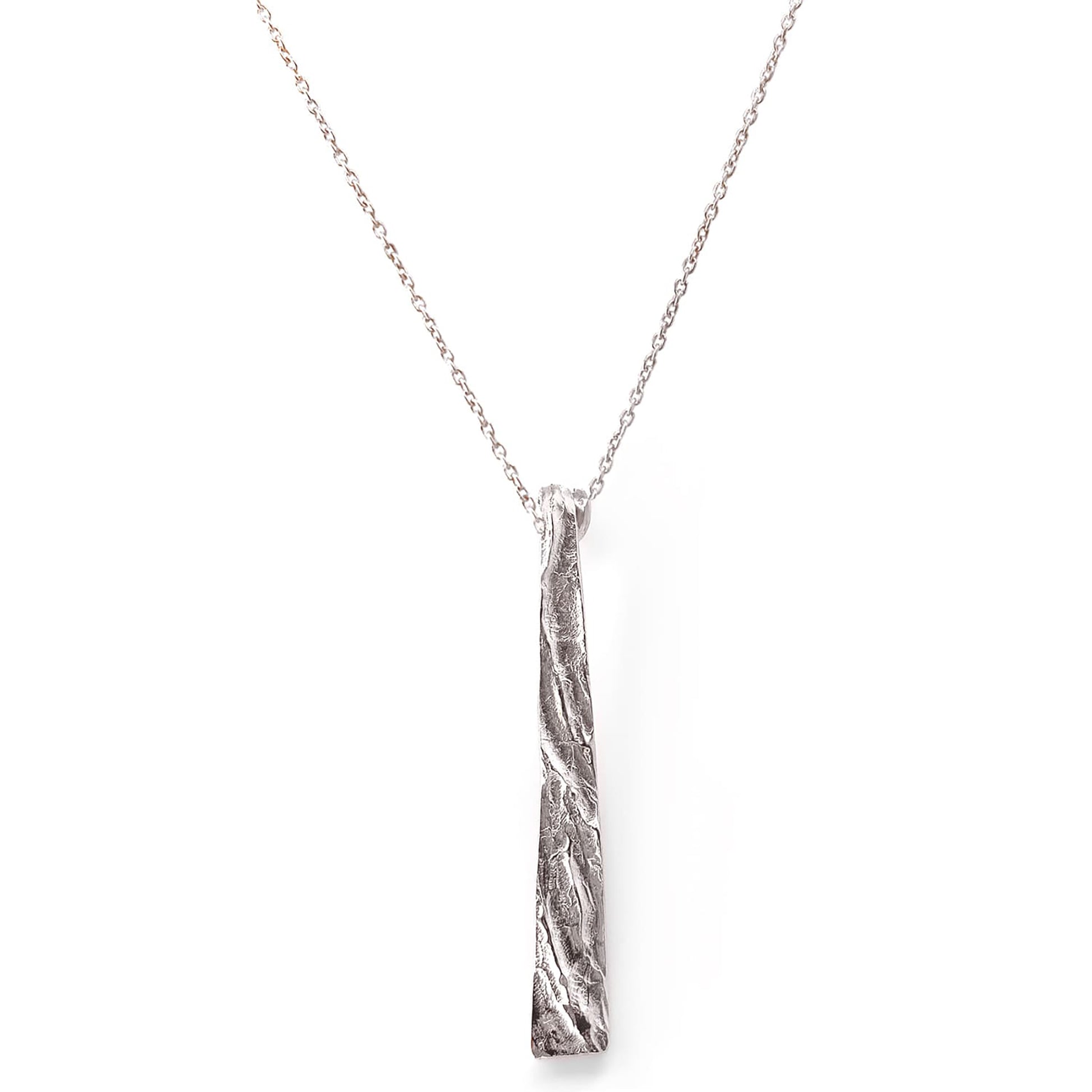 Introducing the Tribu Necklace by FR | Art Jewellery, a gold necklace featuring a long, textured, vertical bar pendant. The pendant boasts an organic, uneven surface and gracefully hangs from a delicate gold chain. This piece of handmade jewellery is minimalist yet striking, offering a touch of artisanal elegance that you can personalize with custom-made orders.