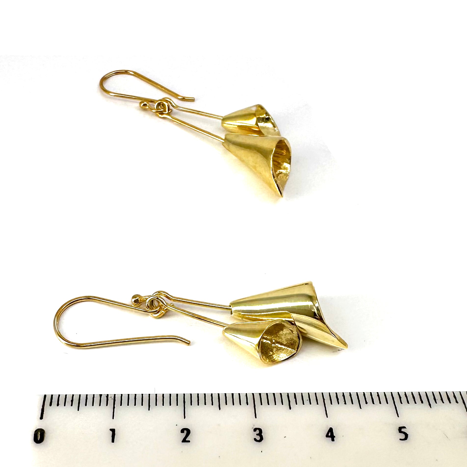 A close-up of two handmade Tulip Earrings by FR | Art Jewellery, each featuring intricately crafted cone-shaped pendants plated in gold. Positioned near a ruler, the earrings measure approximately 5 centimeters in length each. They are designed with hooks for wearing and showcase exquisite craftsmanship, making them perfect for custom-made orders.