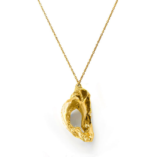 The worldious Necklace by FR | Art Jewellery showcases a gold pendant with a rough, abstract design featuring an irregular hollow section. It is suspended on a delicate gold chain, offering a modern and artisanal aesthetic that captures the essence of handmade jewellery.