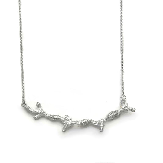 The Branches Necklace from FR | Art Jewellery features a delicate silver chain and a pendant shaped like a textured, intricate tree branch, capturing the essence of handmade jewellery and natural design.